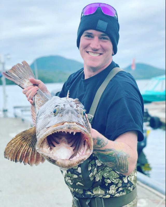 A chef holding a whole fish at the dock