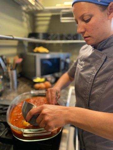 A chef finishing a sauce on the stove